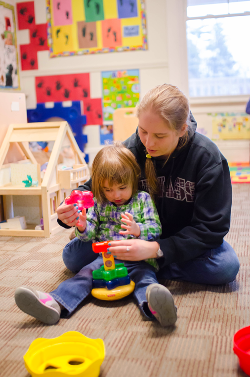 A teacher playing with a small child in a classroom